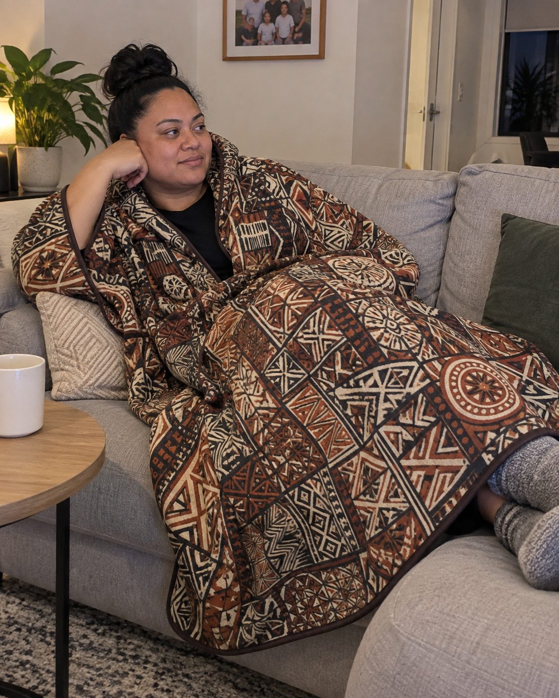 Hooded Blanket in the Elei print, wrapped around someone on the sofa at home.